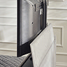 close up image of tv coming out of footboard of light grey ottoman bed
