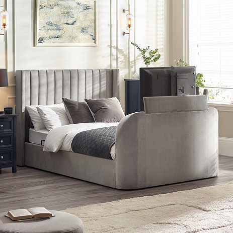 image of light grey fabric ottoman bed with tv coming out of the footboard