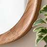 close up image on wooden frame of oval mirror