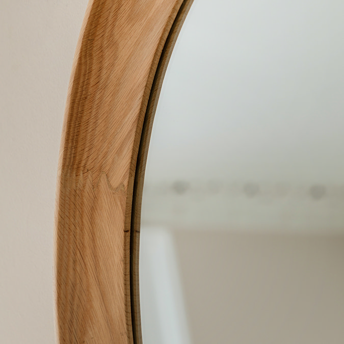 close up image of woodgrain of oval mirror frame
