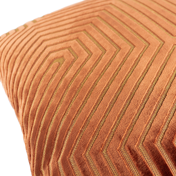 close up on pattern of brick orange cushion with gold geometric.