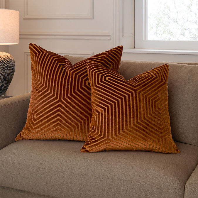 45x45cm brick coloured cushion sat in front of 55x55cm version, sat on light brown sofa