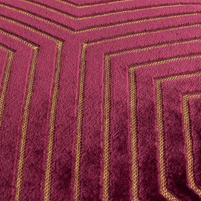 close up on texture of burgundy cushion with gold geometric detailing. 