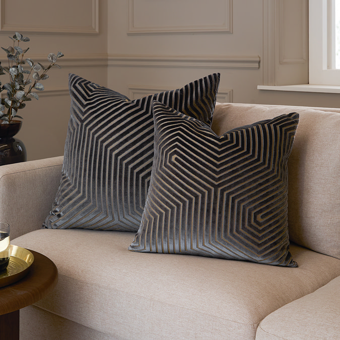pair of grey velvet geometric cushions, one 45x45cm, one 55x55cm, sat together on a cream sofa.