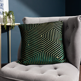 45x45cm emerald green cushion with geometric detailing, sat on grey chair