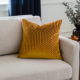 45x45cm gold cushion with geometric detailing, sat in corner of cream sofa