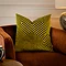 45x45cm olive green cushion with geometric detailing, sat on rust coloured armchair