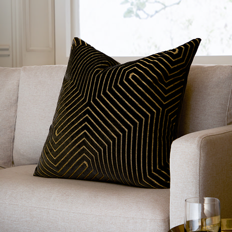 black square cushion with geometric detailing sat on a cream sofa chair