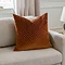 square brick coloured cushion with geometric detailing sat in the corner of a cream sofa