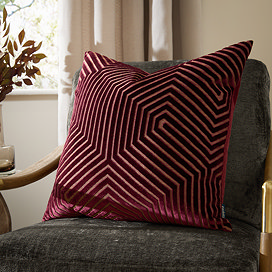 burgundy red cushion with geometric detailing, sat on dark khaki chair