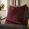 burgundy red cushion with geometric detailing, sat on dark khaki chair
