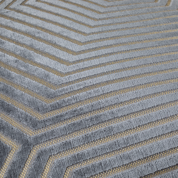 close up of pattern on grey velvet cushion with gold geometric stitch detail