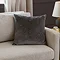 charcoal grey cushion with geometric detailing, sat in corner of cream sofa