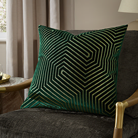 emerald green square cushion with geometric detailing, sat on khaki chair