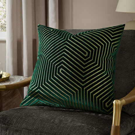 emerald green square cushion with geometric detailing, sat on khaki chair