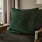 emerald green square cushion with geometric detailing, sat on khaki chair