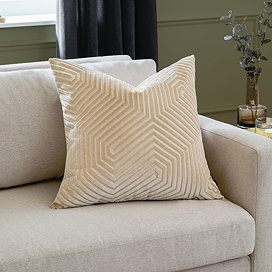 ivory square cushion with geometric detailing sat on cream sofa