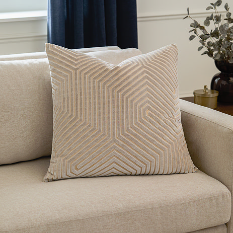 square oyster cream coloured cushion with geometric detailing, placed in the corner of cream sofa