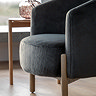 close up image of plush grey accent chair with ash wood legs