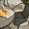close up image of black wicker chair of bistro set, focus on material and the bowl of fruit on table at the side of the shot