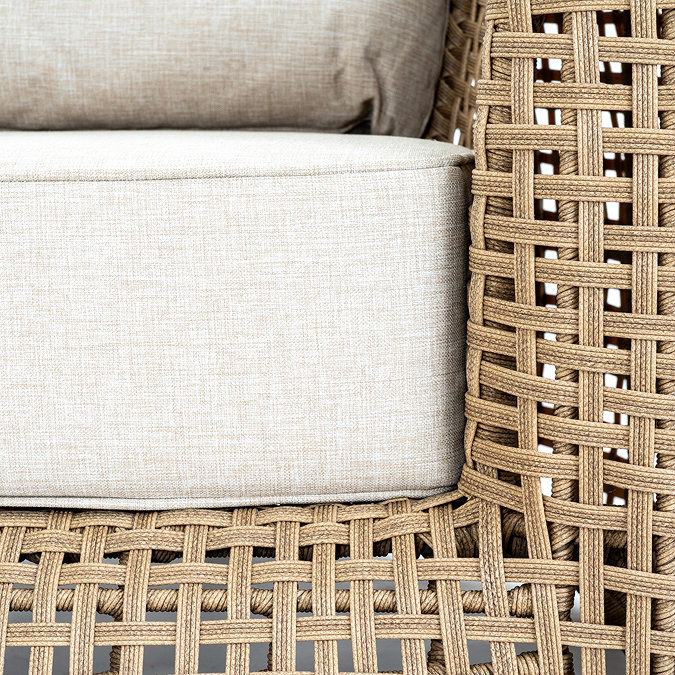 close up image of brown wicker construction of garden armchair with deep plush cushion