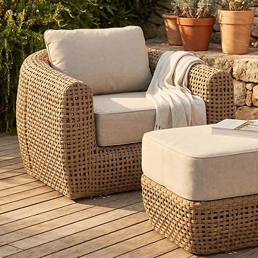 side on image cut out of chunky rattan garden armchair with cream cushions