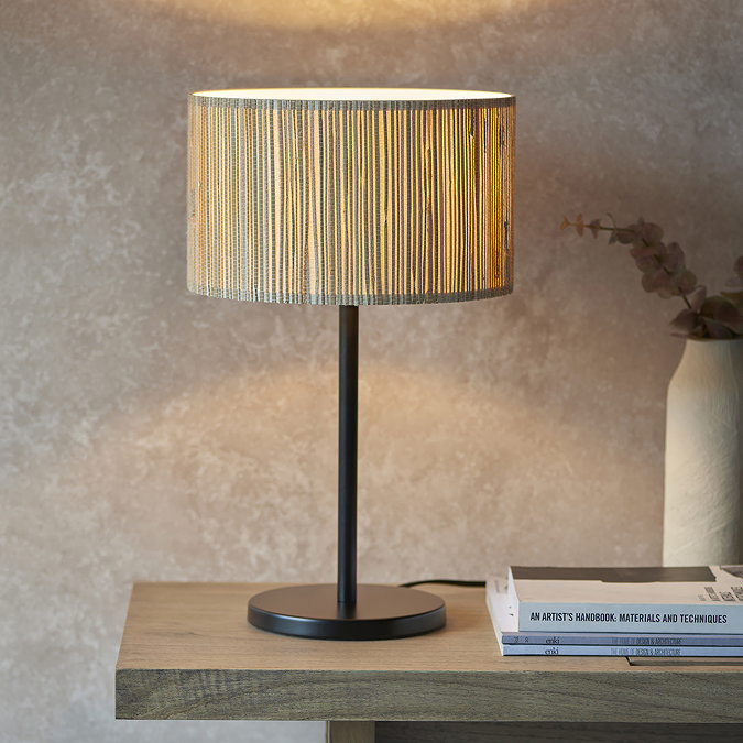 woven seagrass lamp with black steel base on a wooden side table