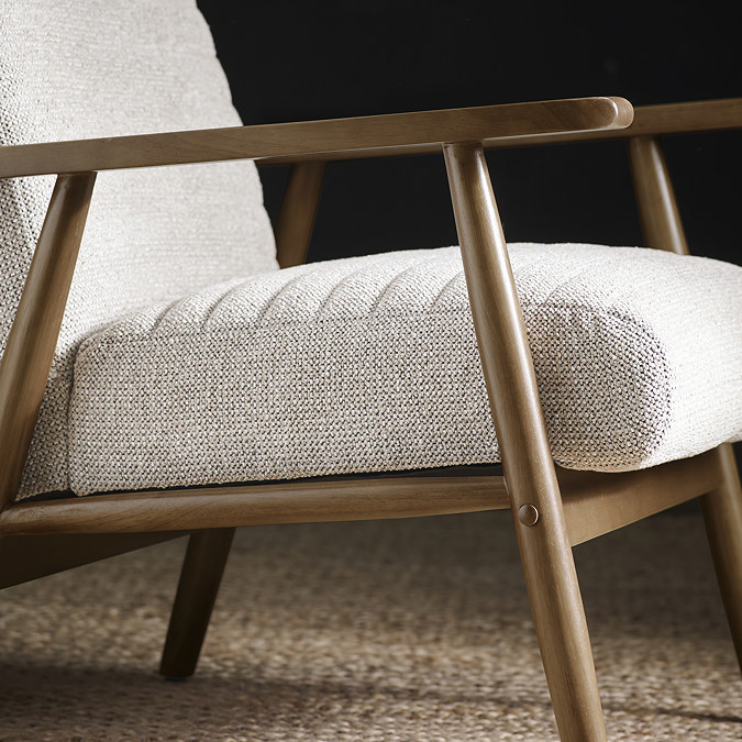 close up image of side of upholstered sand coloured accent chair with warm brown wooden arms and legs