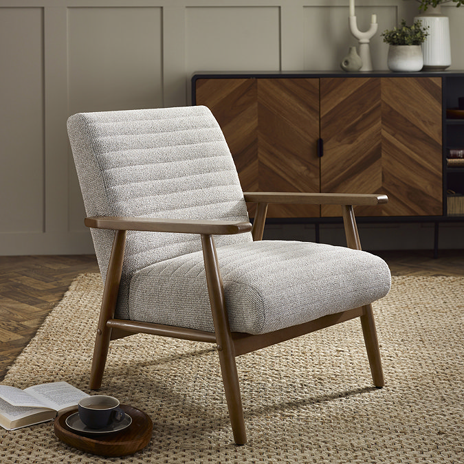 image of accent chair with upholstered sand coloured material and warm brown arms and legs, on a jute rug