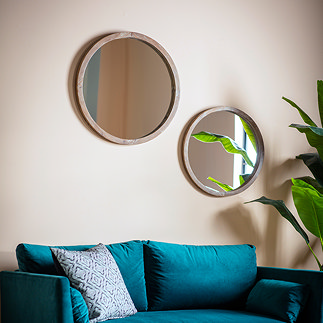 image of two round mirrors on a cream wall above a teal velvet sofa