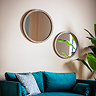 image of two round mirrors on a cream wall above a teal velvet sofa