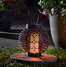 image of round black metal lantern with intricate cut out pattern, light up at night in garden with inner warm light