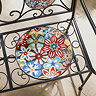 closeup image of wrought iron bench with mosaic pattern circle seat