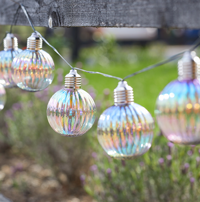 close up on iridescent opal round bulb string lights on a fence in the daytime