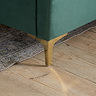 close up image of gold-effect feet of green velvet double bed, on wood floor