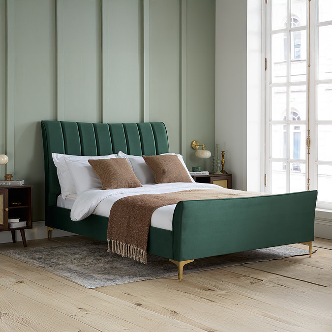image of green velvet double bed with pleated headboard and gold feet, against sage green panelled bedroom wall