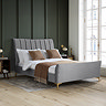 image of double bed with grey velvet pleated headboard and gold legs against grey panelled wall of bedroom