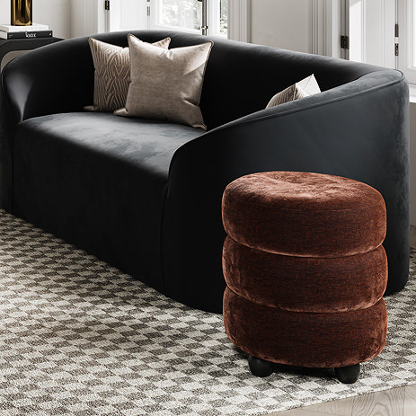 image of brandy brown sculptural velvet chenille pouffe next to black sofa