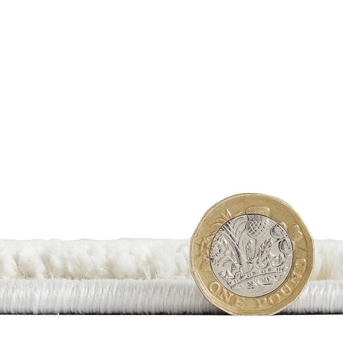 side on image of flat rug with pound coin standing next to it to show rug as half the height of coin