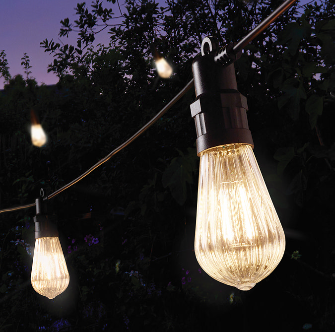 close up image on warm white fluted festoon string light in garden at night