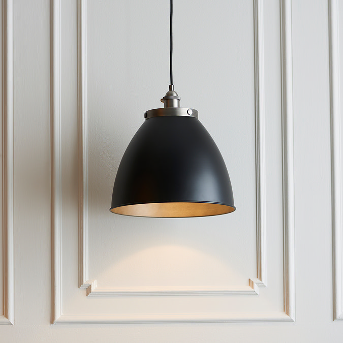 close up image of larger black and pewter pendant light in front of panelled cream wall