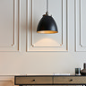 image of larger black pendant lamp hanging above a side table in front of a panelled cream wall