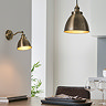 image of antique brass wall light on kitchen wall with matching pendant light hanging above kitchen table