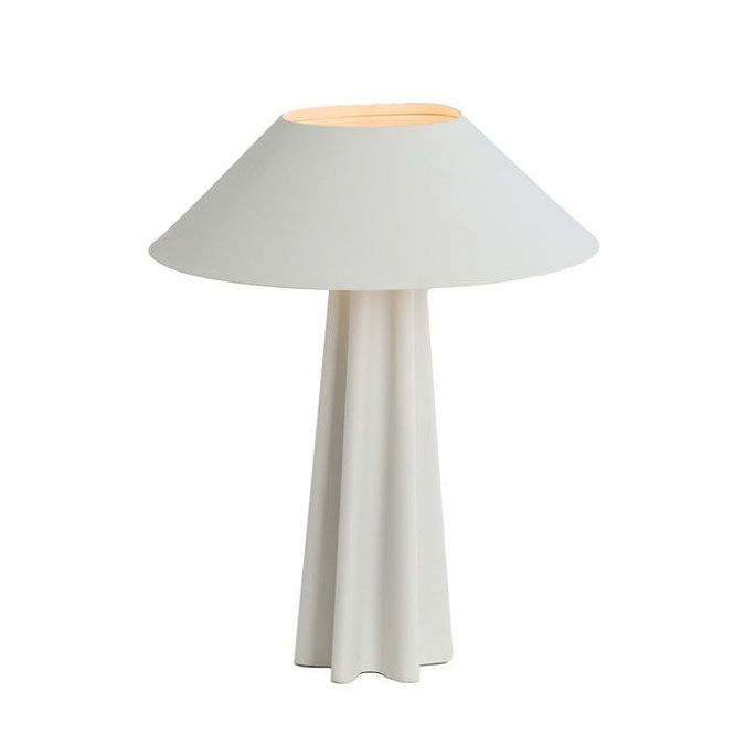 image cut out on white background of matt white sculpted lamp, with bulb on emitting soft orange glow