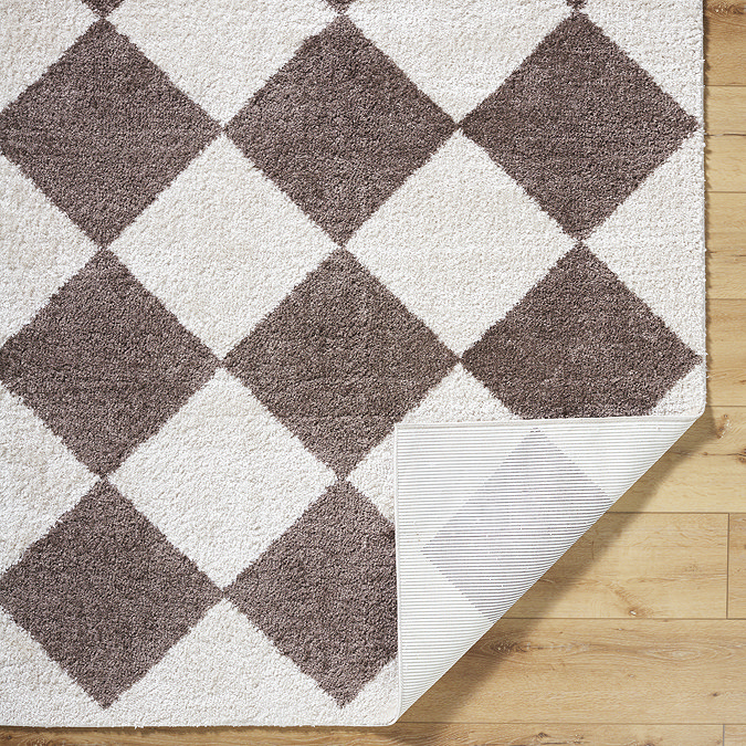 close up image of brown diamond rug folded over at corner to reveal material underneath