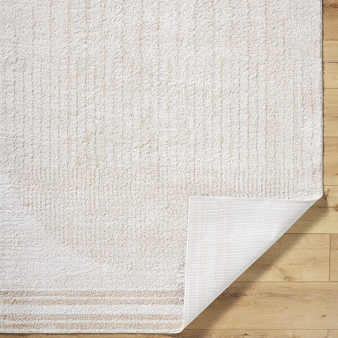 close up image of cream and beige rug with corner folded over to reveal material underneath