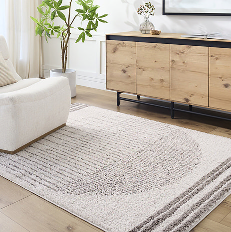 image of cream rug with modern brown central circle design, on light wood living room floor