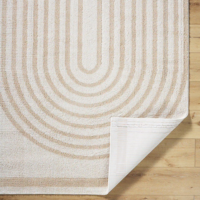 close up image of beige and cream line arch rug with corner folded up to show material underneath