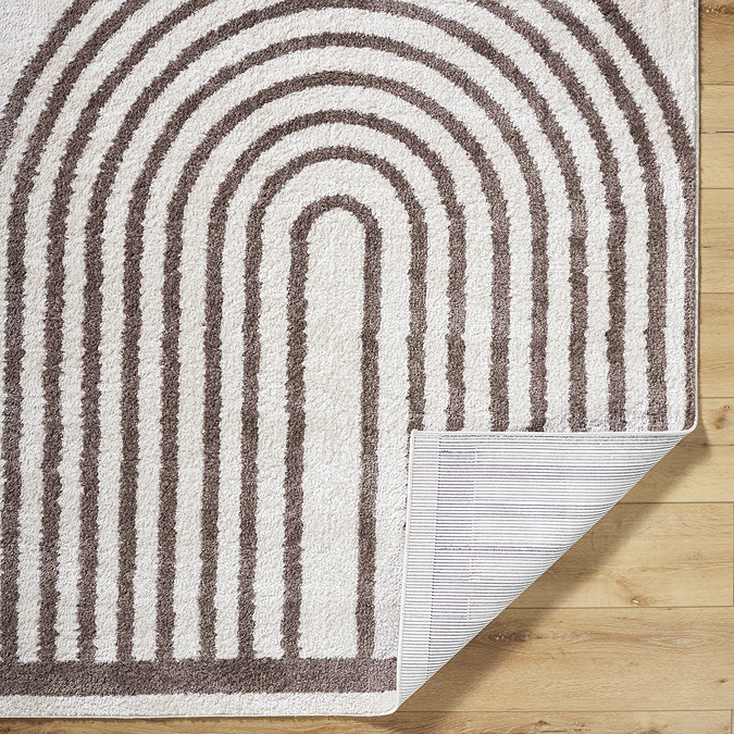 close up image of brown and cream soft rug with arch pattern, corner folded up to show material underneath
