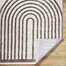 close up image of brown and cream soft rug with arch pattern, corner folded up to show material underneath